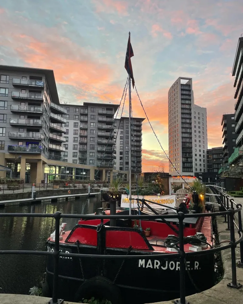 The Hold Fast Leeds floating bookshop aboard the historic coal barge Marjorie R. moored at Leeds Dock at sunset